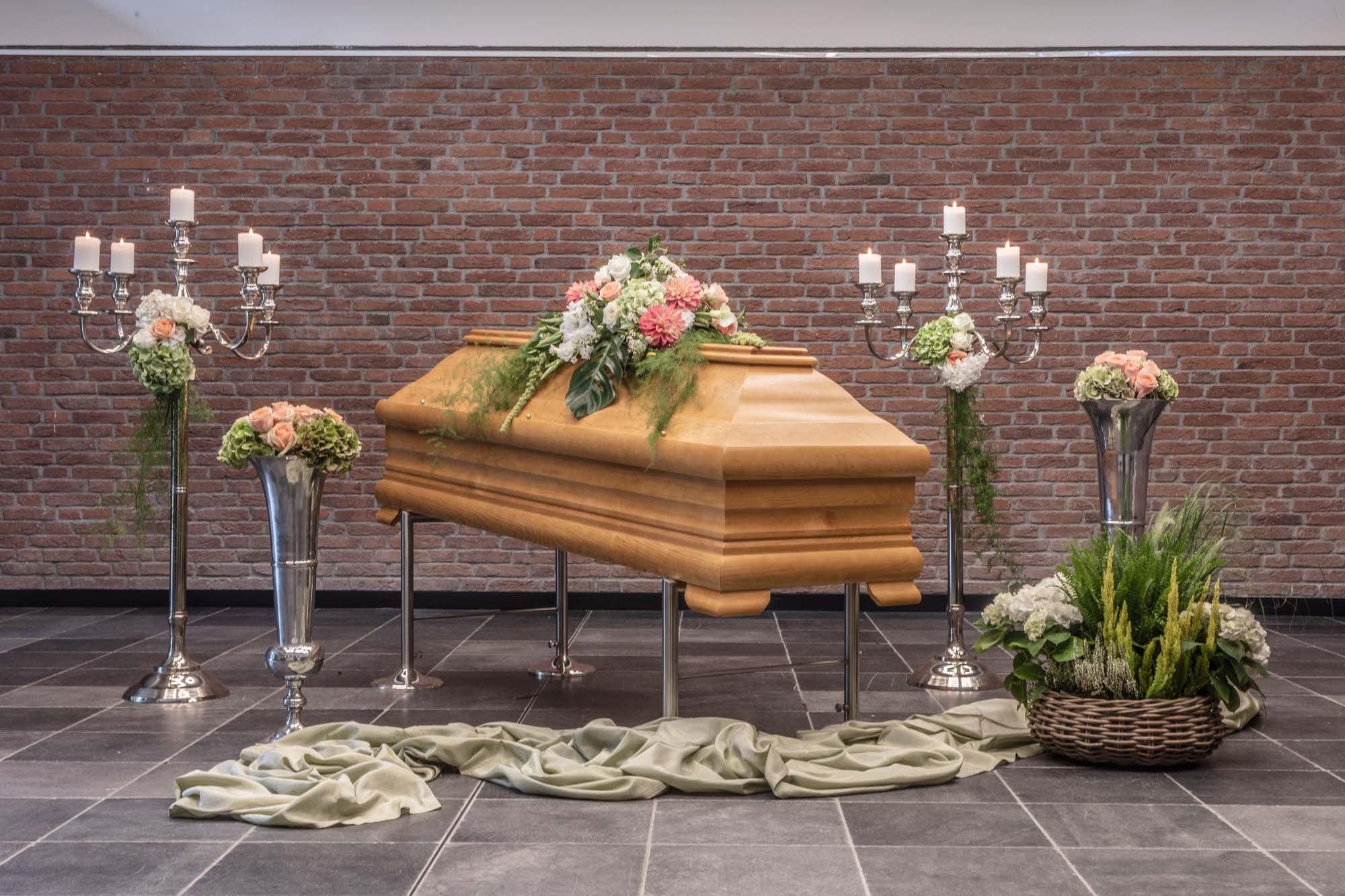 Aufgebahrter Sarg mit Blumenschmuck und Kerzen