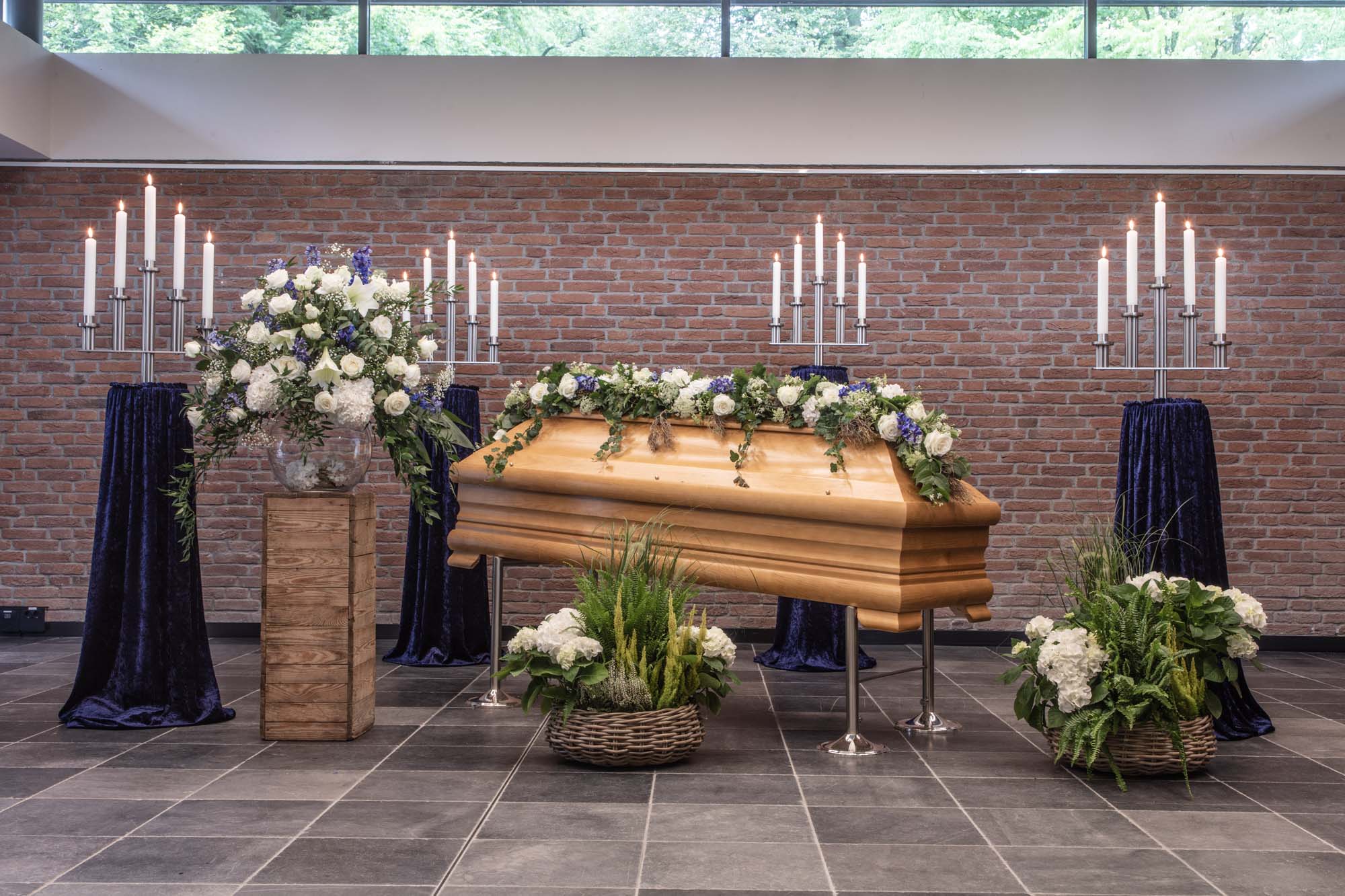 Sarg mit Blumen und hohen Kerzenleuchtern