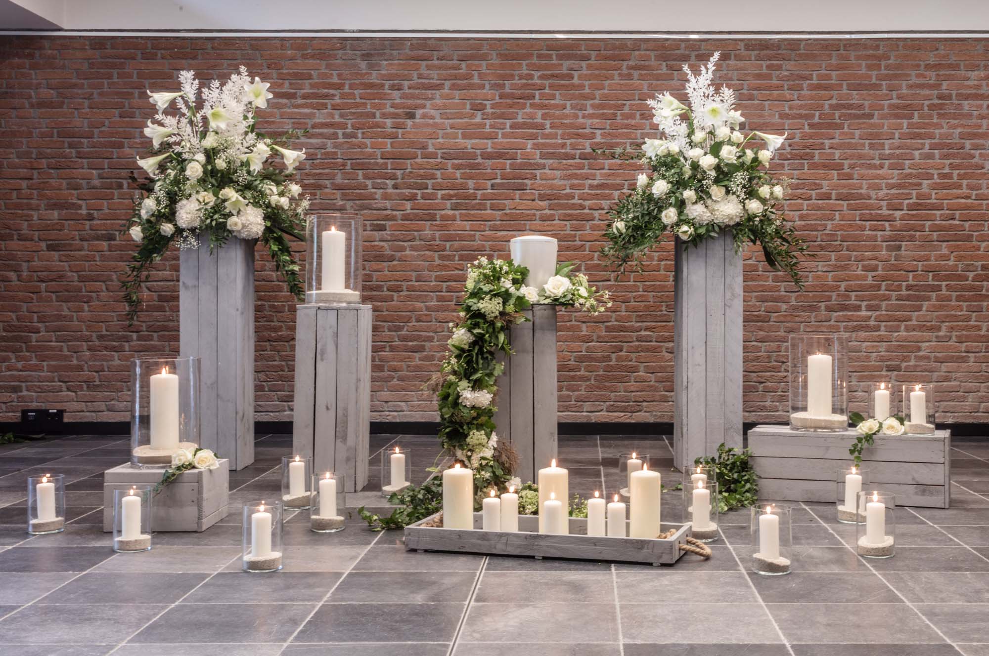 Weißes Blumenarrangement mit Kerzen und Säulen