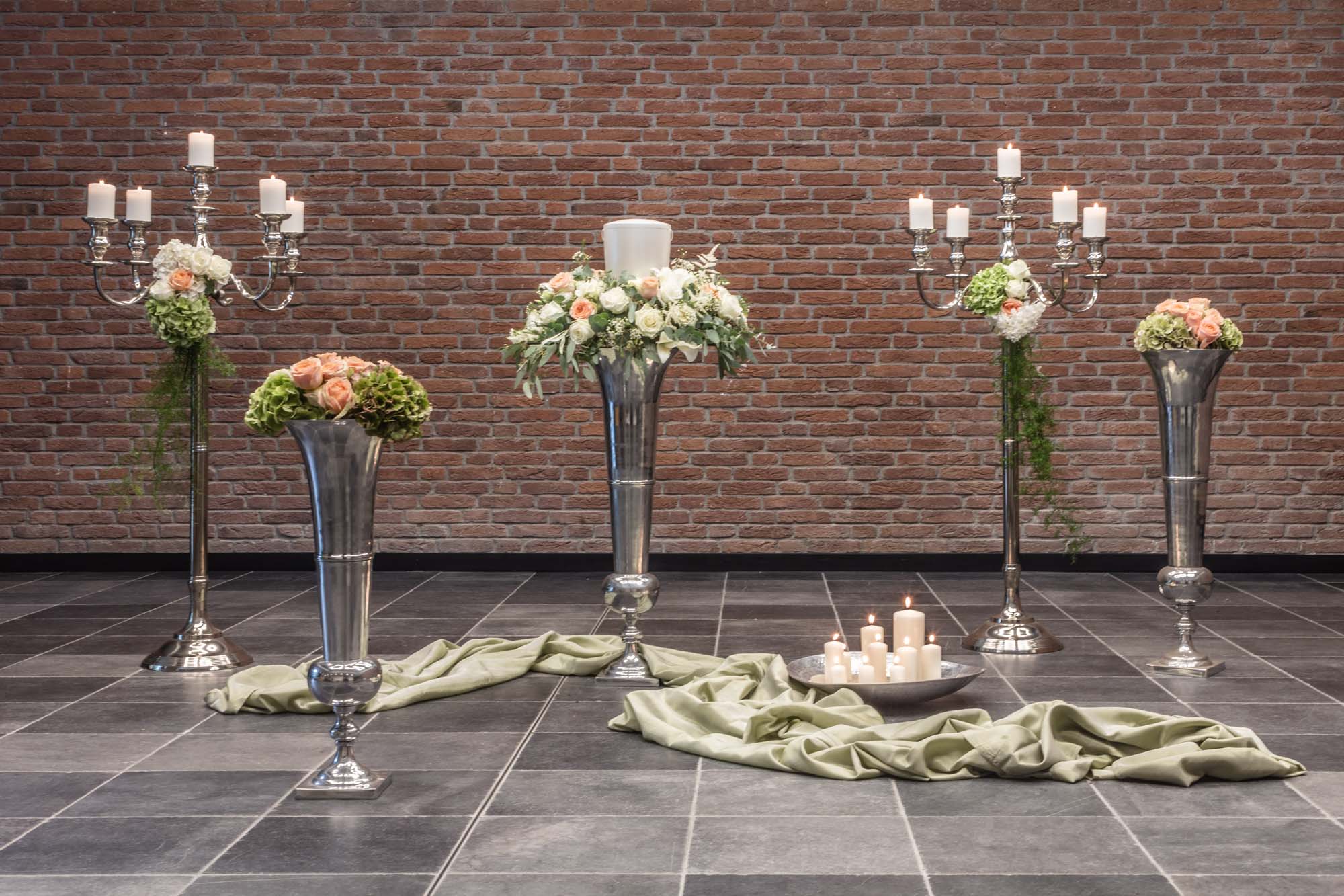 Silberne Vasen mit Rosen und Kerzen auf grünem Tuch