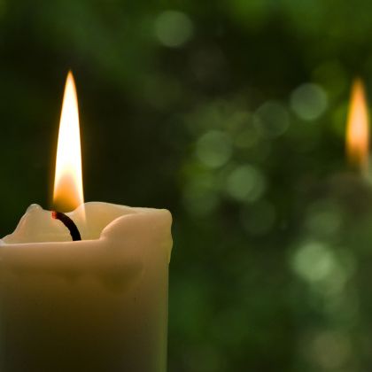Brennende Kerze vor grünem Hintergrund